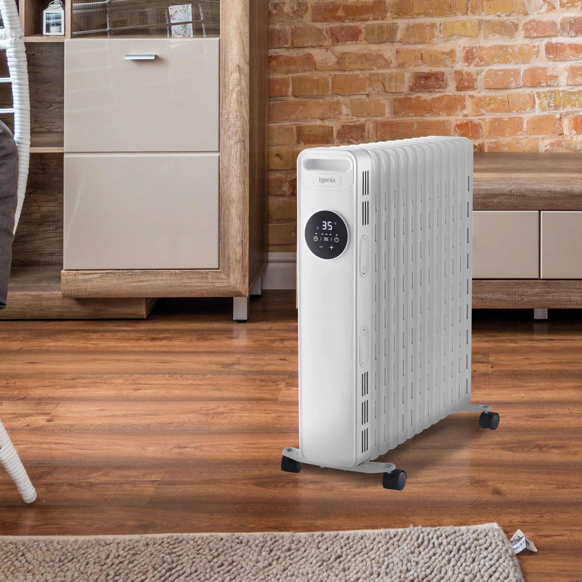 A white portable oil-filled radiator heater with digital controls stands on a wooden floor in a cozy living room with brick walls and modern furniture.