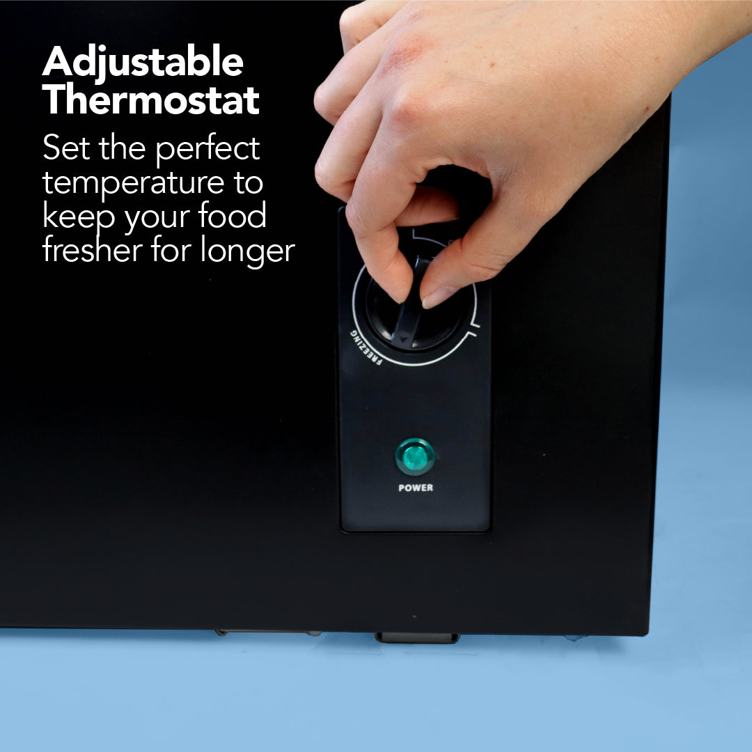 A hand adjusts the thermostat on the Igenix Freestanding Chest Freezer, 99 Litre, black, with a green power light. Adjustable Thermostat: Enjoy extra freezer storage and set the ideal temperature to keep food fresher longer.