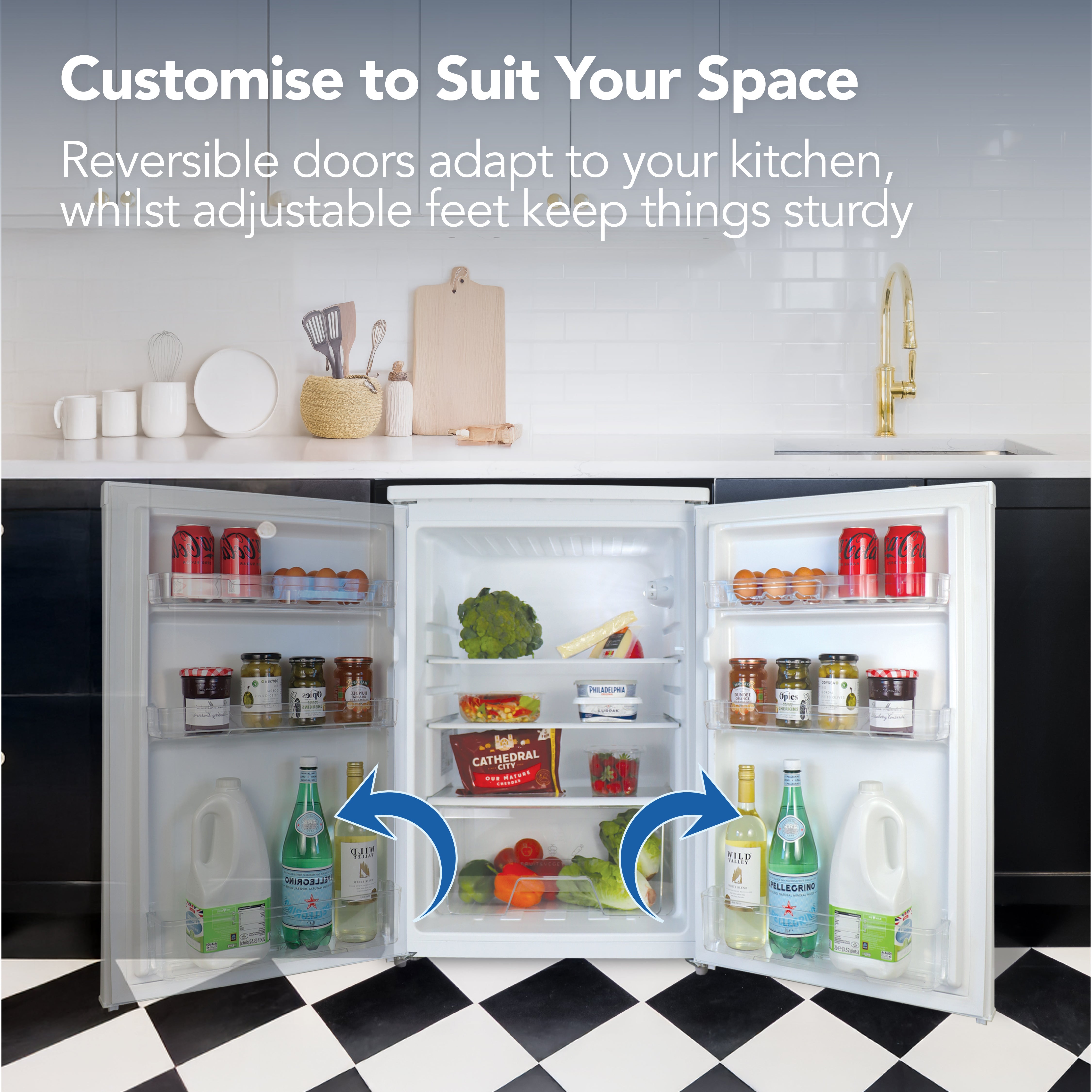 The Igenix Under Counter Larder Fridge (131 Litre, White) sits in a modern kitchen with food and drinks arranged inside. Text highlights reversible doors, adjustable feet, and glass shelves for flexible storage. Blue arrows indicate door movement.