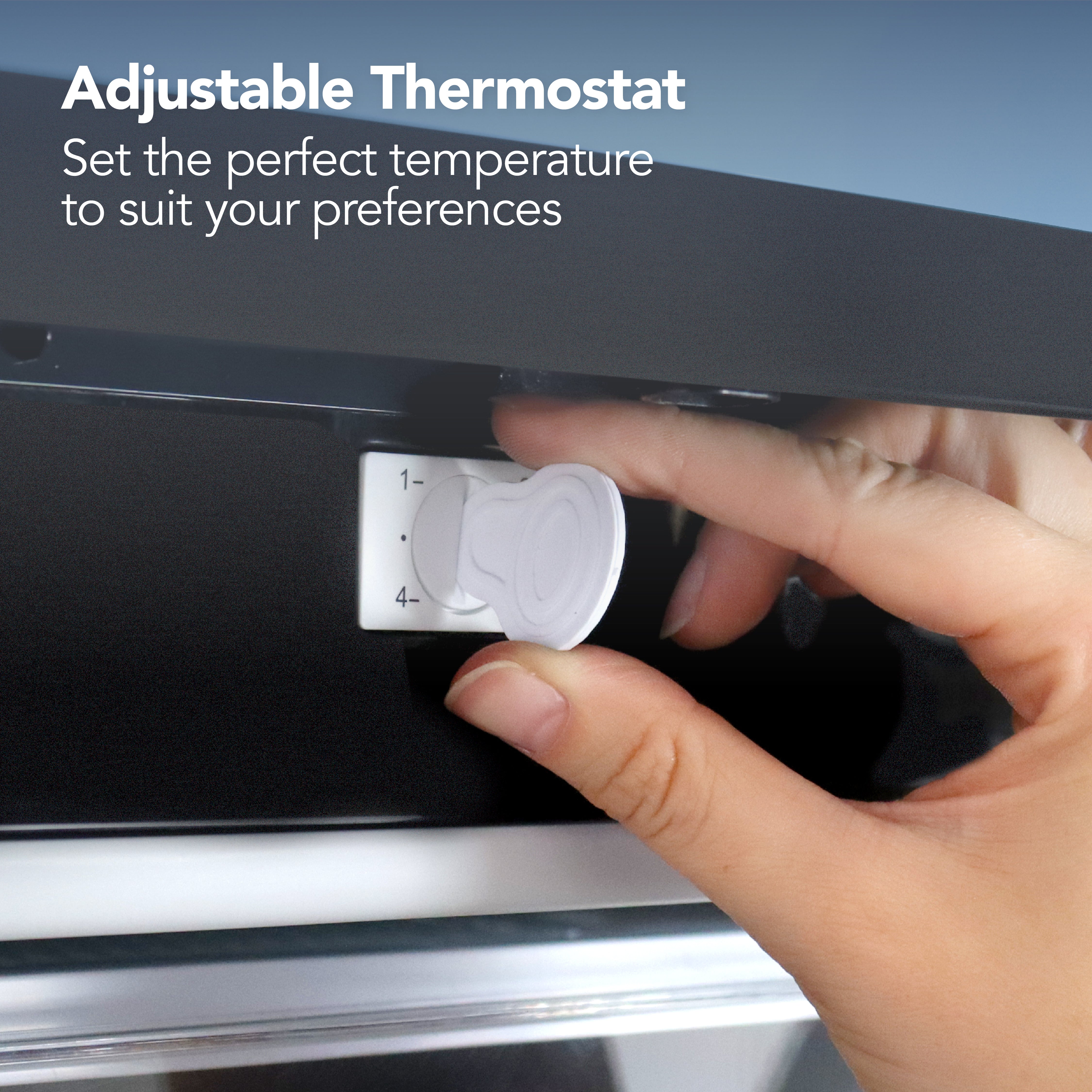 A hand adjusts the white thermostat dial on the Igenix Under Counter Freezer, 88 Litre, Black with reversible doors. Text above reads: Adjustable Thermostat – Set the perfect temperature to suit your preferences.