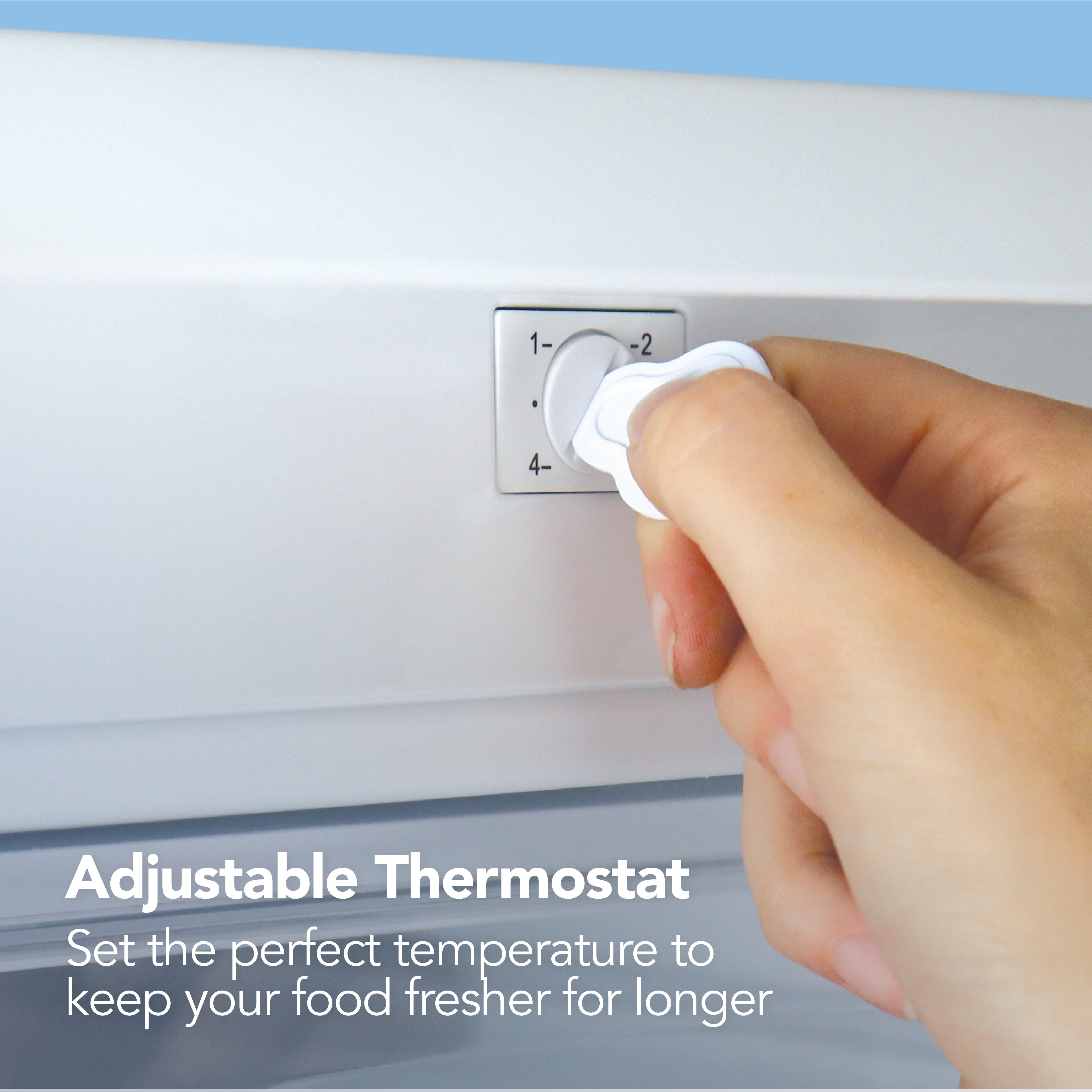A hand adjusts the thermostat on the Igenix Under Counter Freezer (88L, Reversible Doors, White), with text reading: Adjustable Thermostat. Easily set your ideal temperature to keep food fresher for longer.