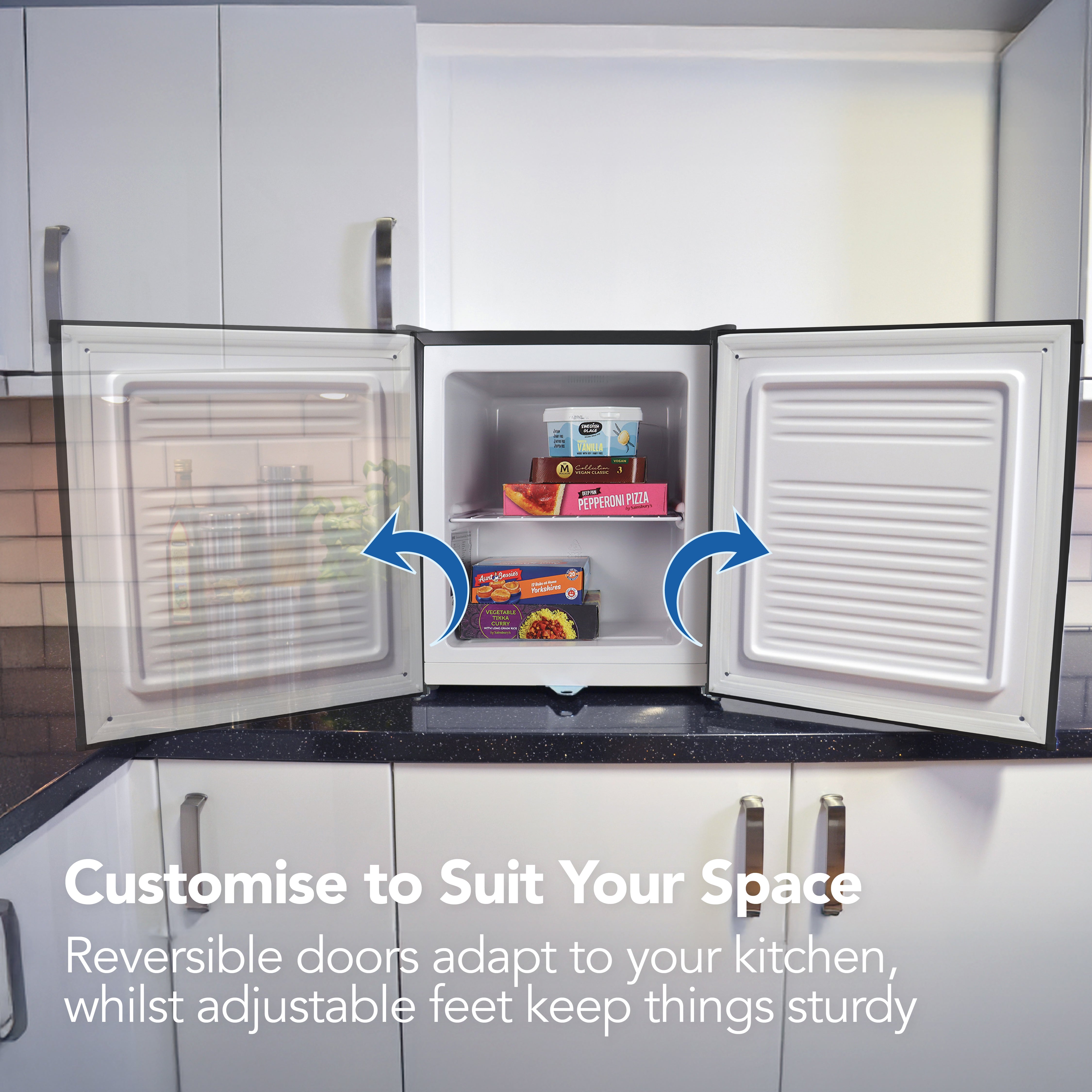 The Igenix Table Top Freezer with Lockable Door, 33 Litre, in black sits open on a kitchen counter. Frozen food is inside. Text reads: Customise to Suit Your Space—reversible doors and adjustable feet fit any kitchen.