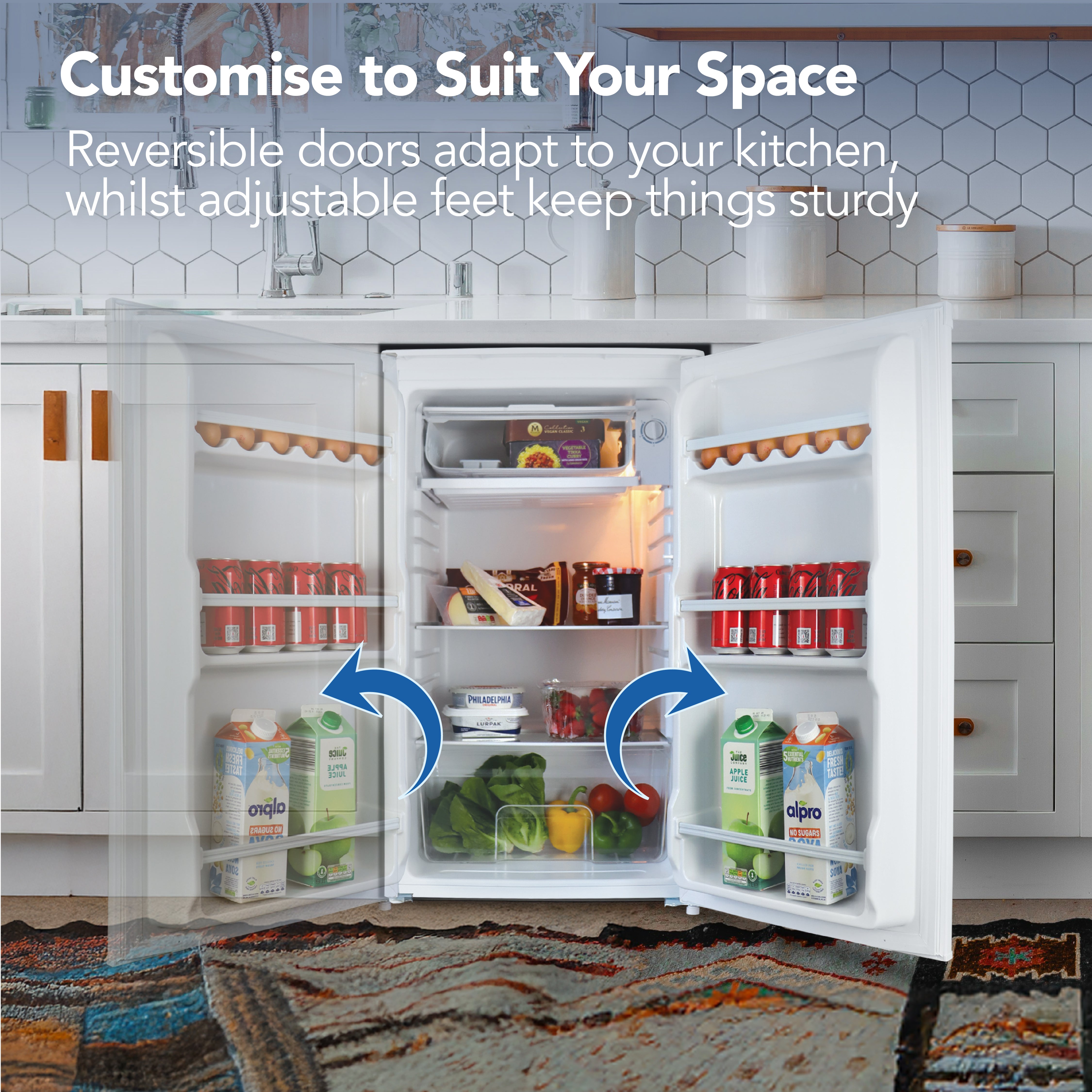 The Igenix Under Counter Fridge with Chill Box (91 L, White) is shown with both doors open, stocked with drinks and food. Text above highlights customisable features like reversible doors and adjustable feet; blue arrows show its flexibility.