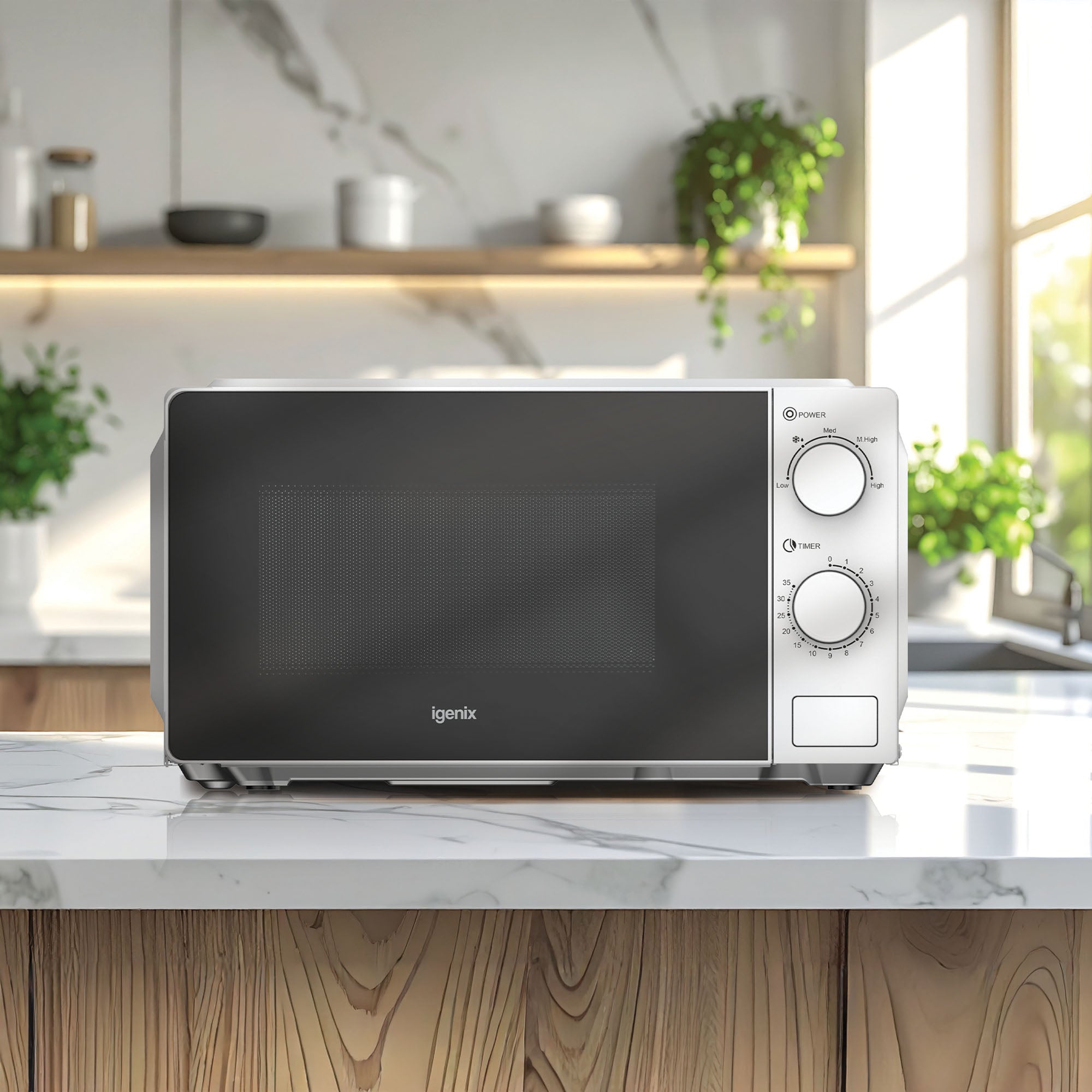 An Igenix IGMS02071W white manual microwave (700 W, 20L, 35 min timer) sits on a marble kitchen counter; shelves with plants, jars, and a sunlit window appear in the background.