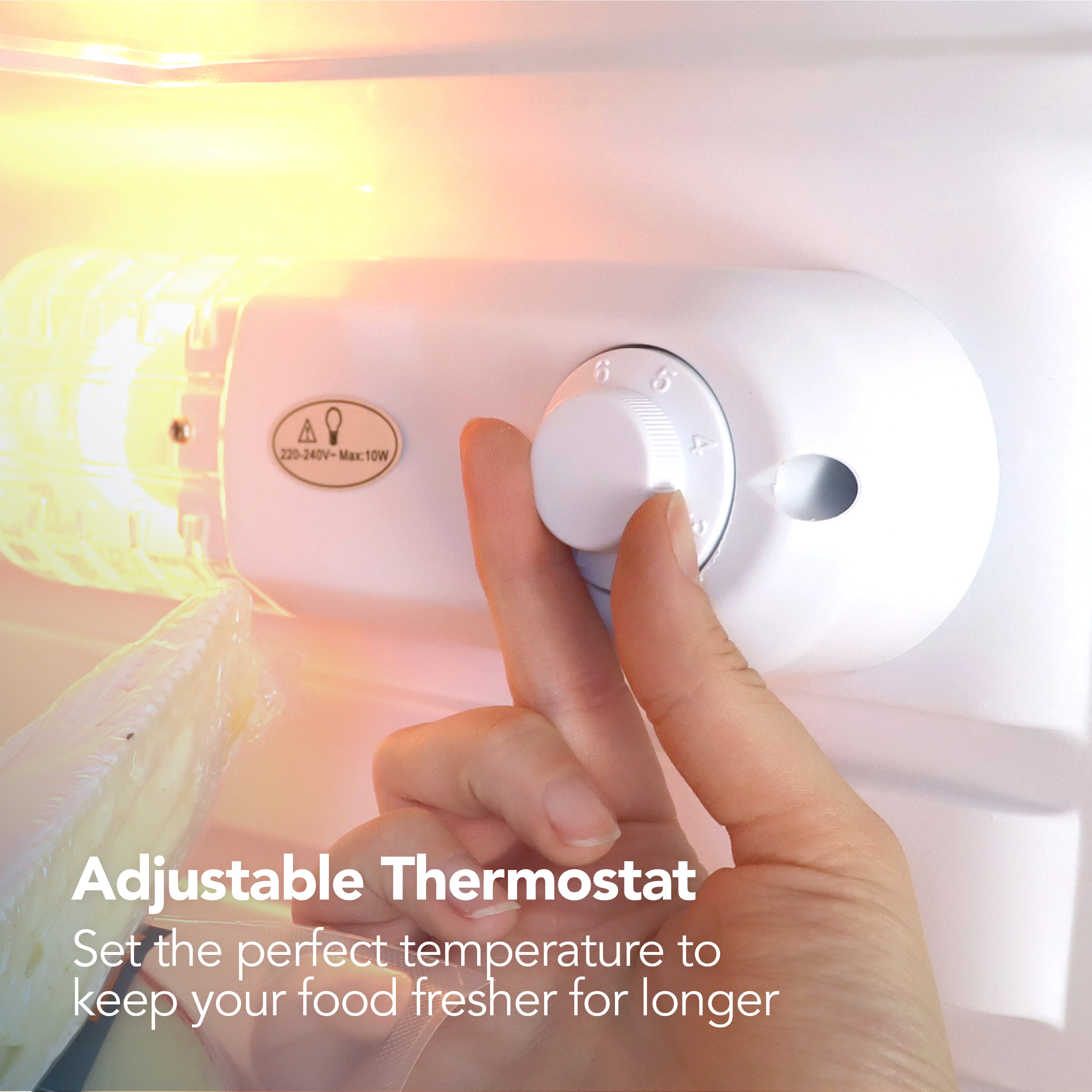 A hand adjusts the thermostat inside the Igenix Under Counter Larder Fridge, 127 Litre, Silver. Text: Adjustable Thermostat – Easily set the ideal temperature to keep your food fresher for longer.