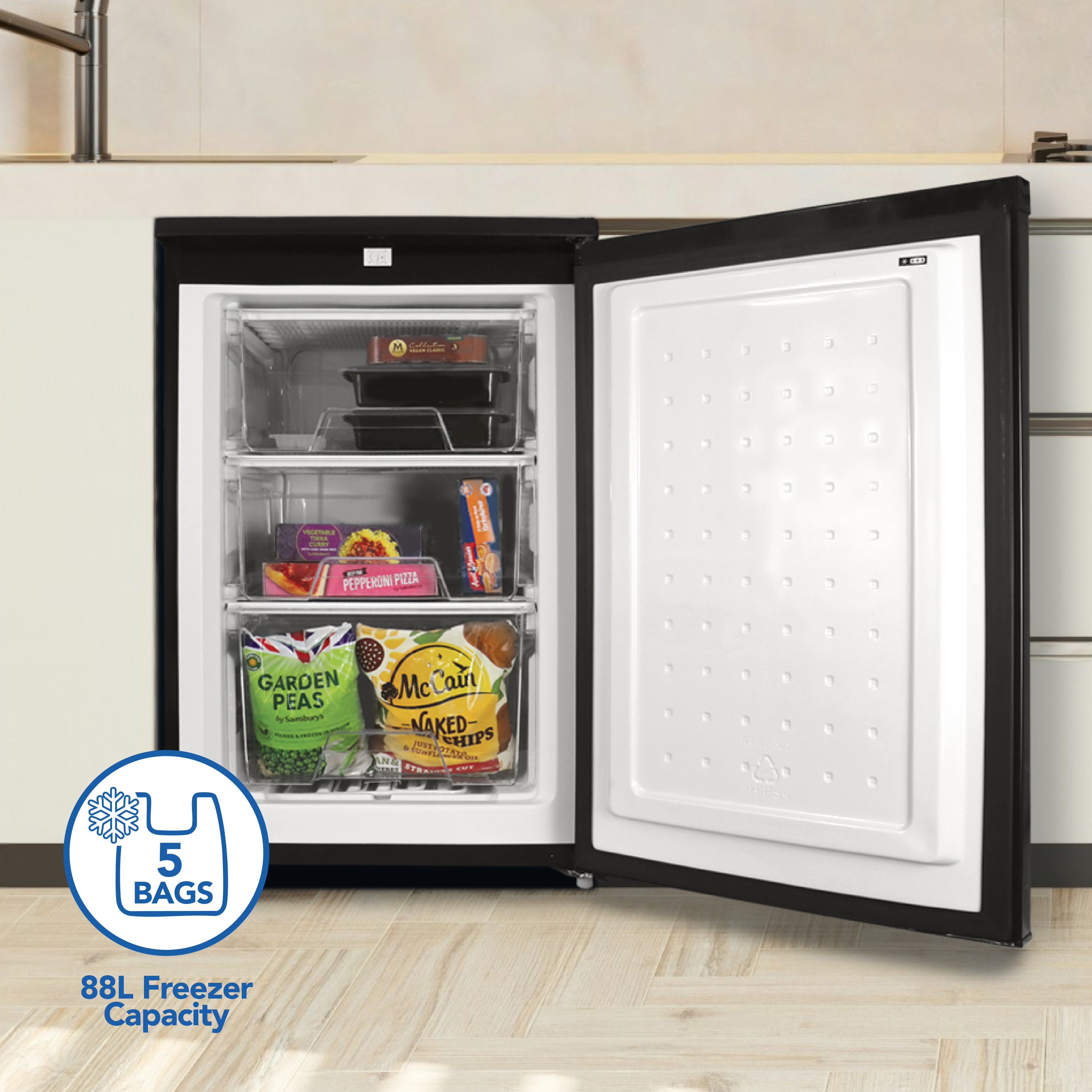 The Igenix Under Counter Freezer, 88 Litre in black, features three shelves stocked with frozen foods like vegetables and fries. Its compact design includes reversible doors and a “5 bags, 88L freezer capacity” graphic on the bottom left.