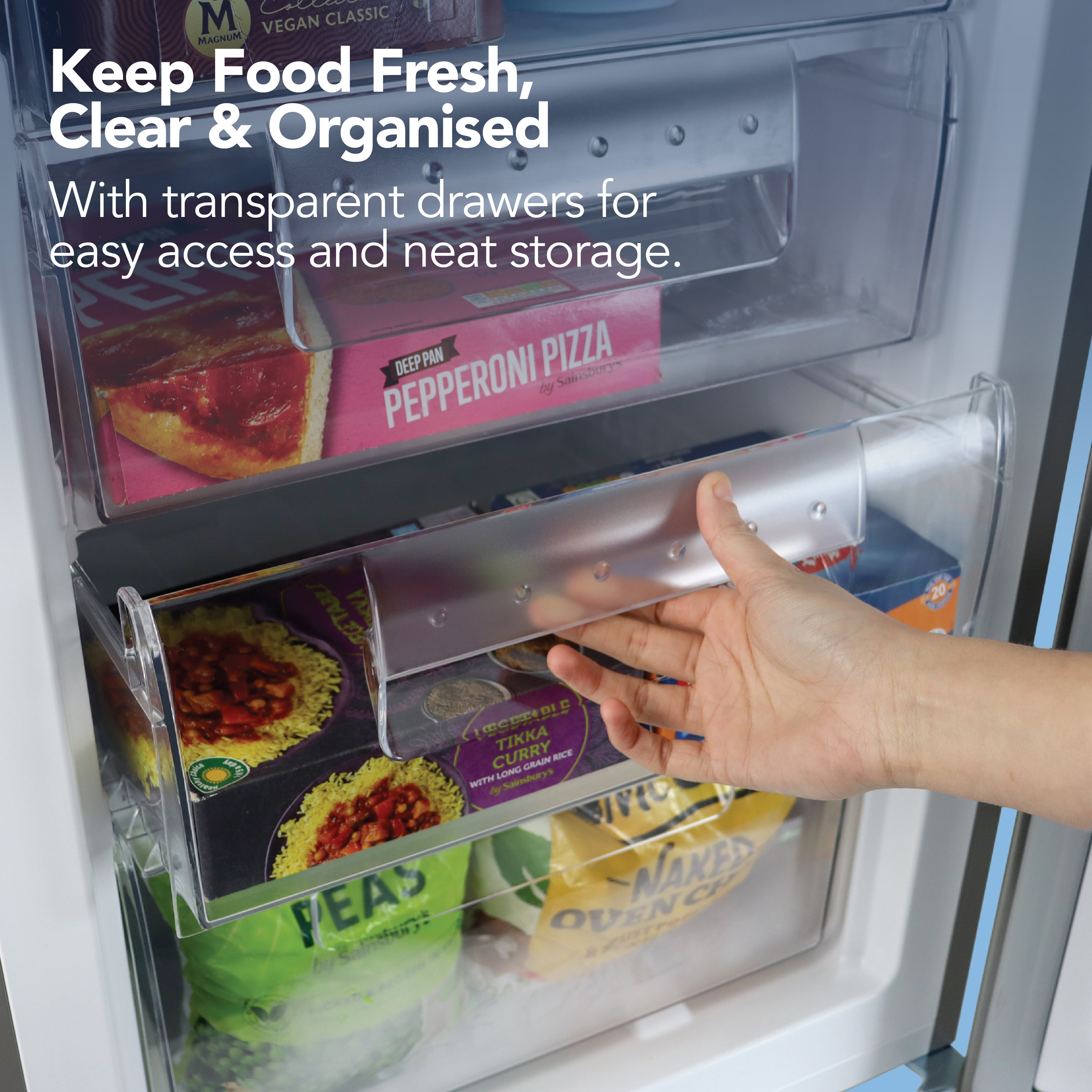 A hand opens a clear freezer drawer filled with neatly packed frozen foods inside the sleek silver Igenix Under Counter Freezer, 91 Litre, Reversible Doors. Text reads: “Keep Food Fresh, Clear & Organised. Transparent drawers make access and storage simple and neat.”.
