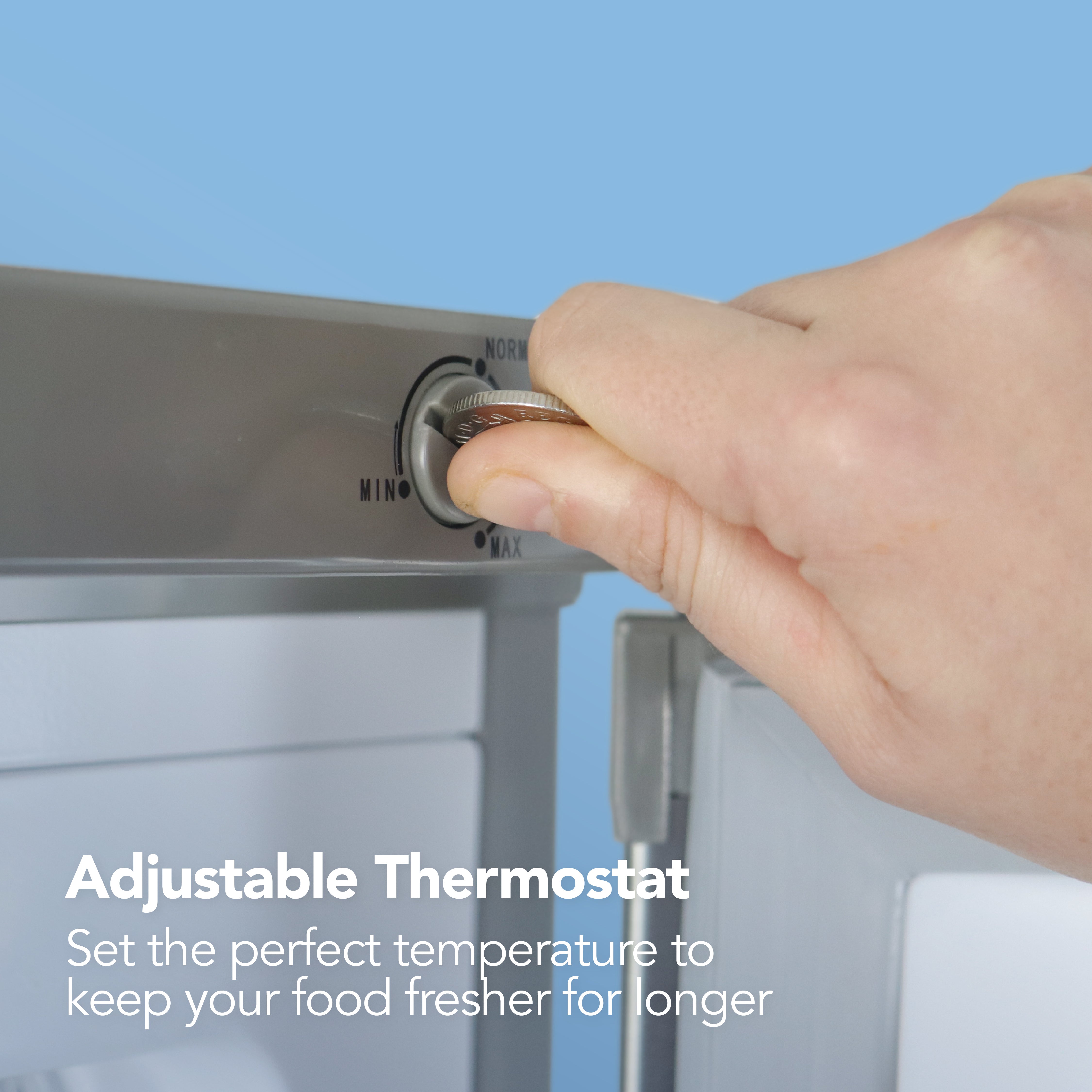 A hand turns the adjustable thermostat dial on the sleek Igenix Under Counter Freezer, 91 Litre, Silver. Text reads: Adjustable Thermostat. Set the ideal temperature in your Igenix under counter freezer to keep your food fresher for longer.
