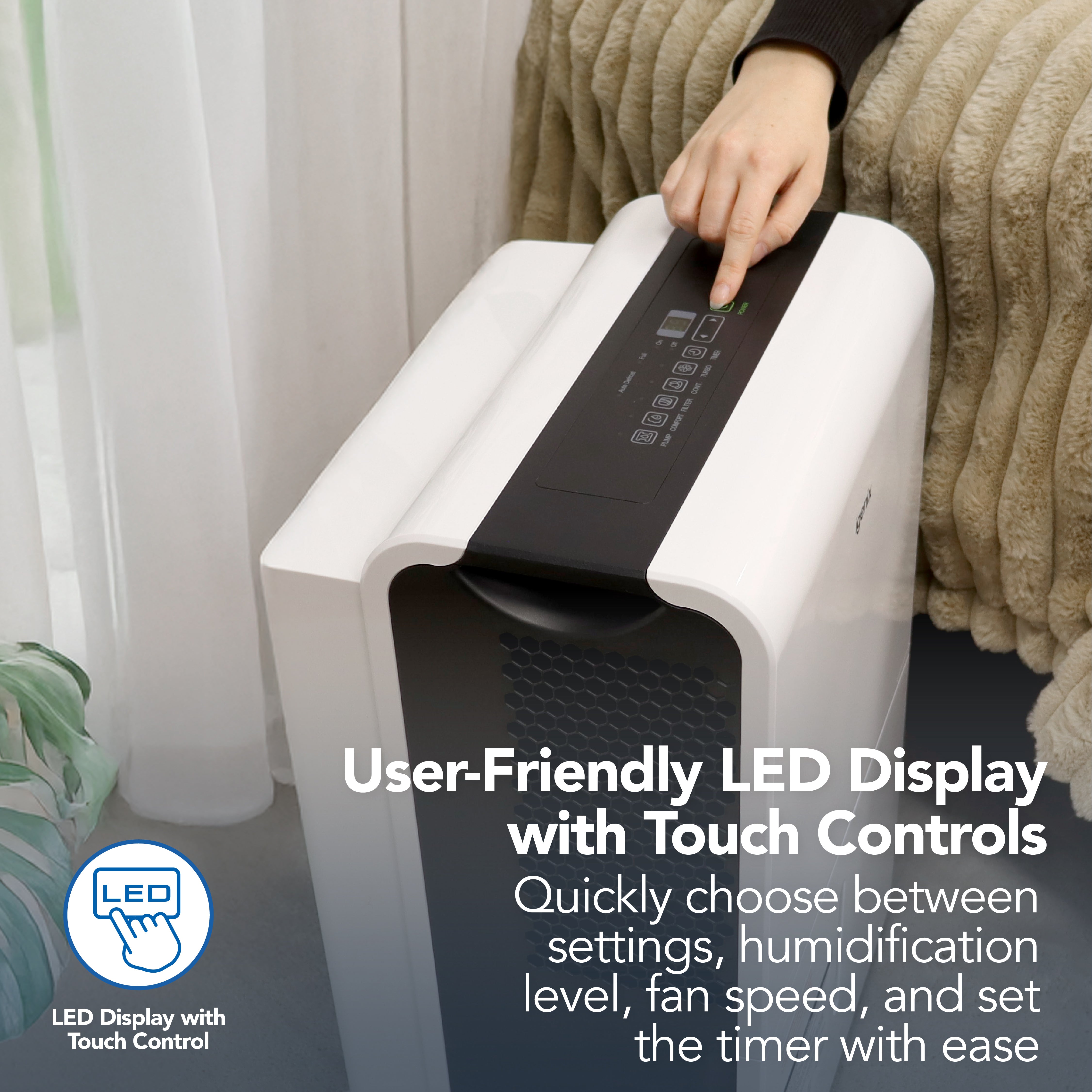 A person uses the Igenix Portable Dehumidifier, which extracts 50 litres per day, adjusting settings via its LED touch control panel for easy selection of humidity level, fan speed, and timer.