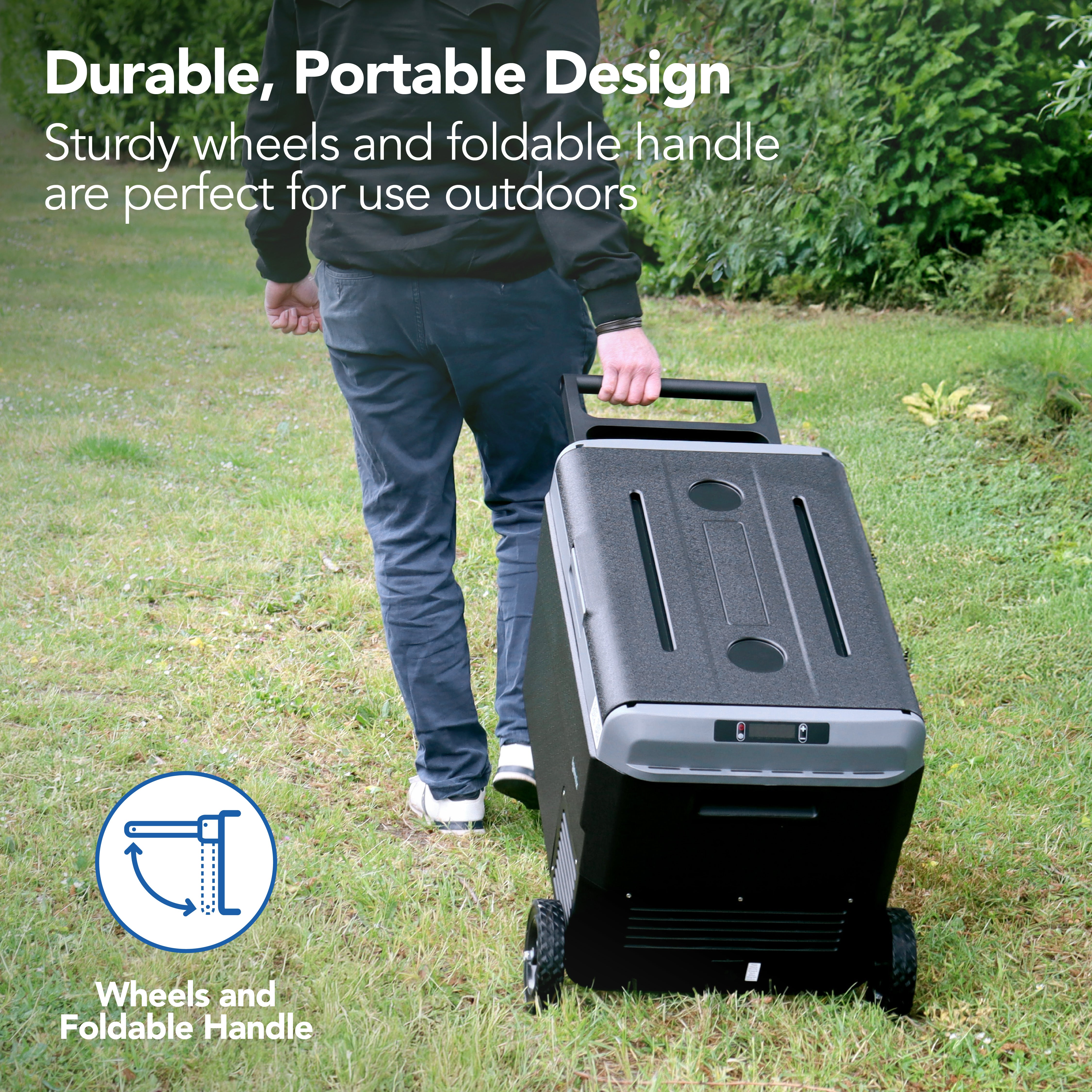 A person pulls the Igenix 50L Portable Fridge Freezer, Black, with sturdy wheels and a foldable handle across grass. Text: Durable, portable design—ideal for outdoor use.