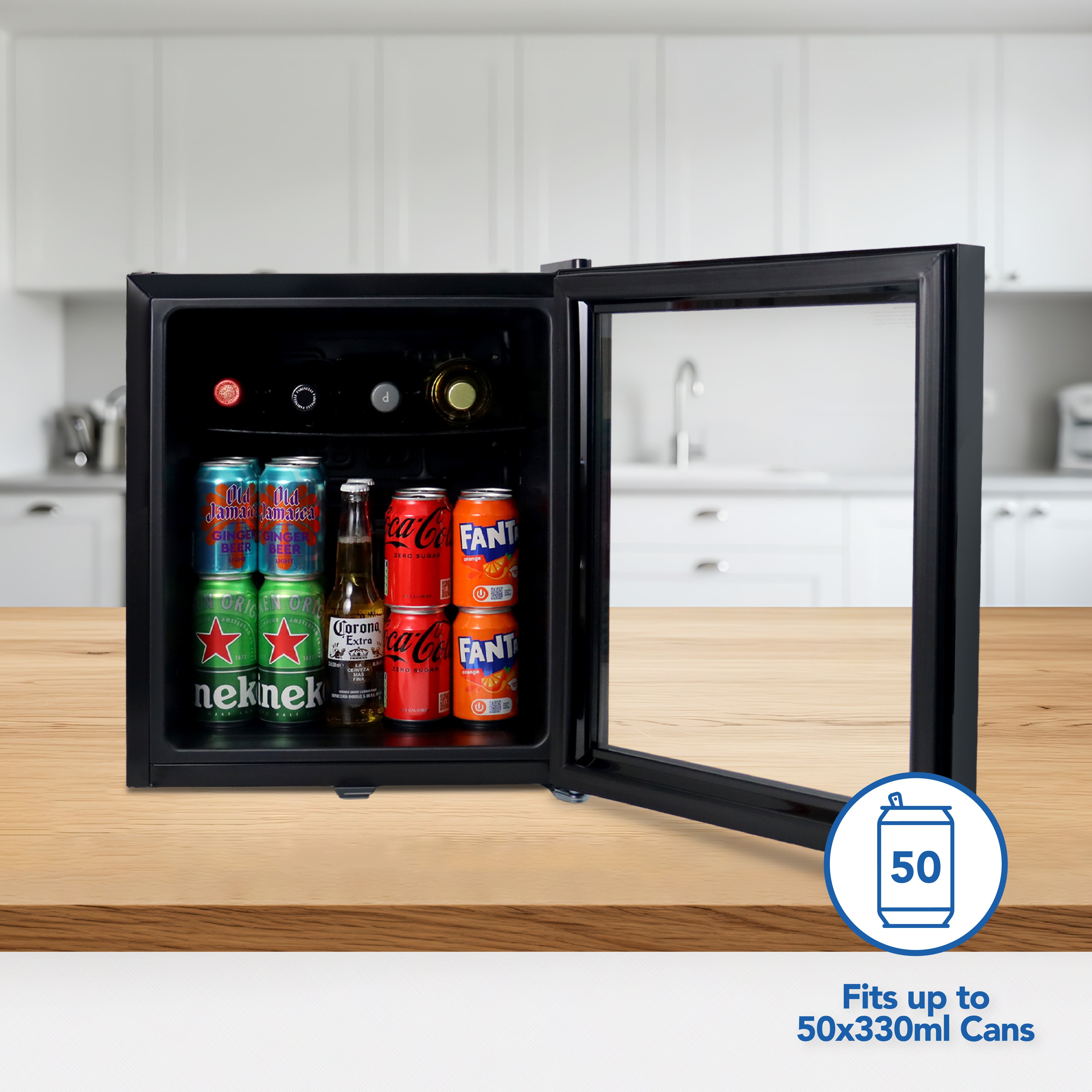The Igenix Tabletop Drinks Fridge, 48 Litre, in black sits on a kitchen counter with its door open, revealing assorted cans and bottles inside. This compact fridge can fit up to 50 cans of 330ml each.