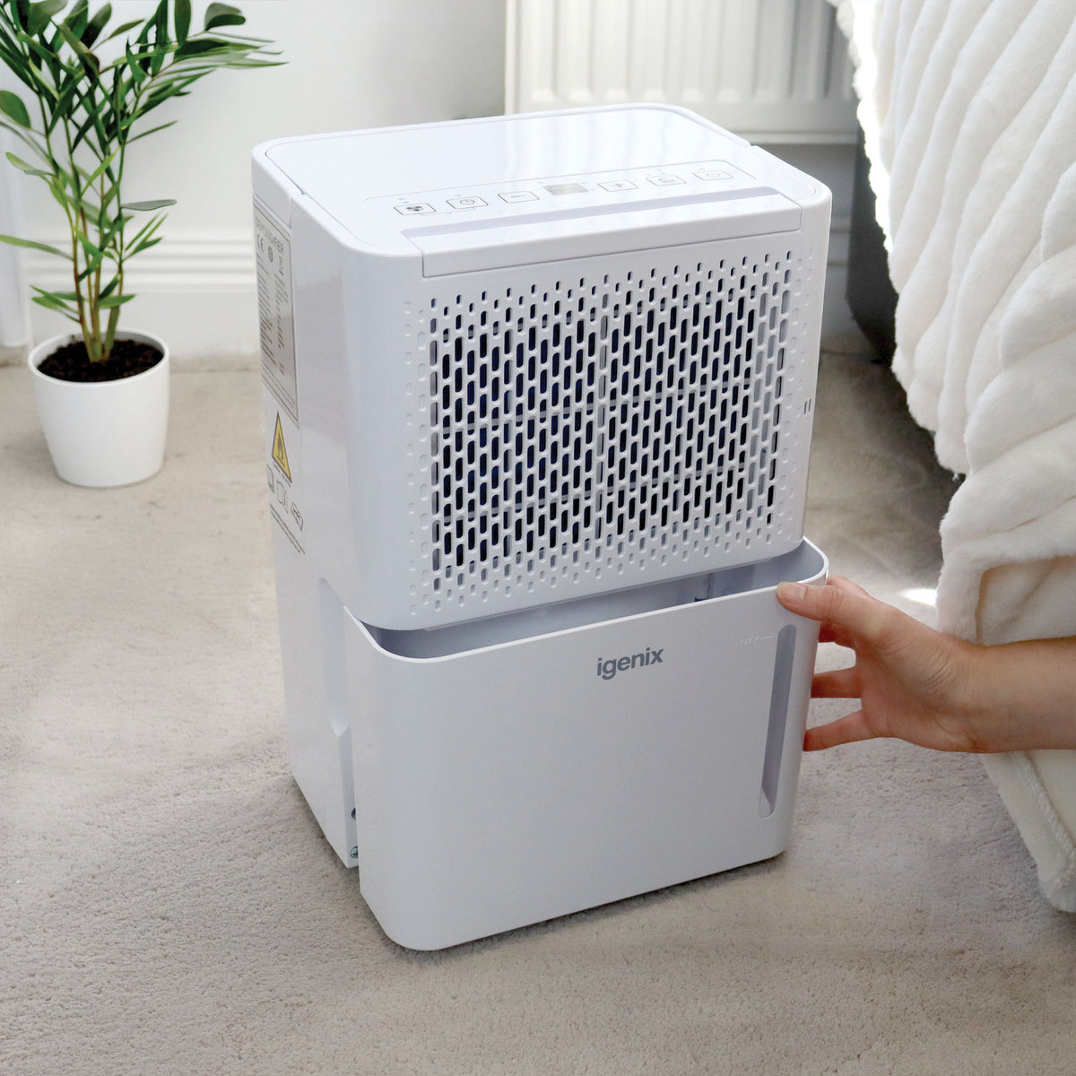A hand slides the water collection tank out of a white Igenix Portable Dehumidifier, Extracts 12 Litres per Day.