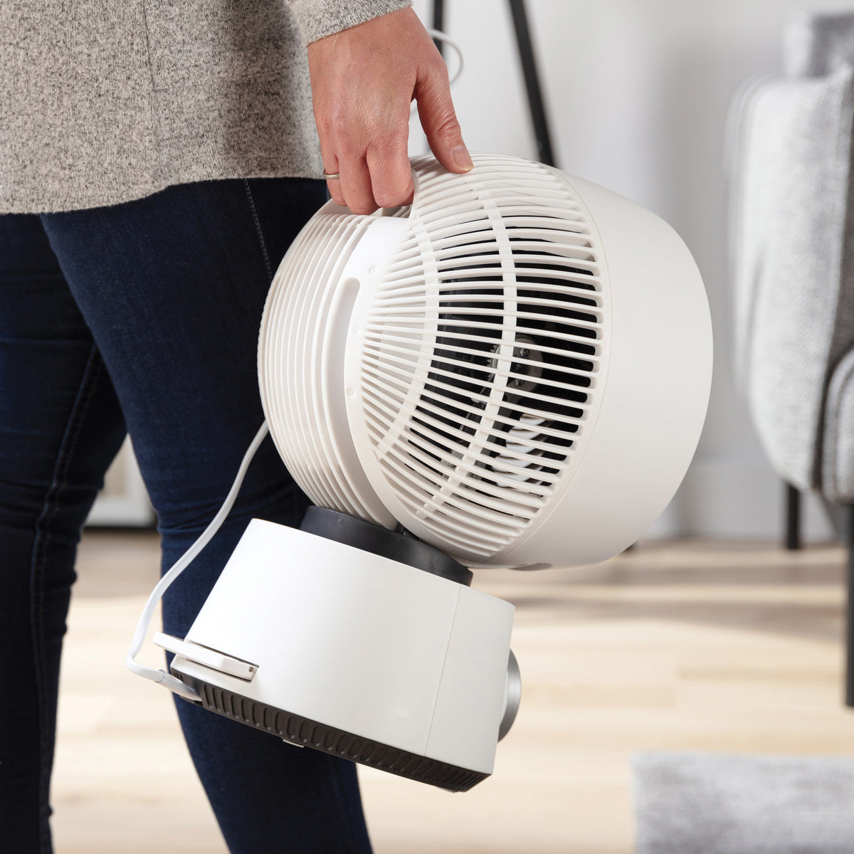 A person carries a white Igenix Digital Air Circulator Turbo Fan, 9 Inch, by its built-in handle.