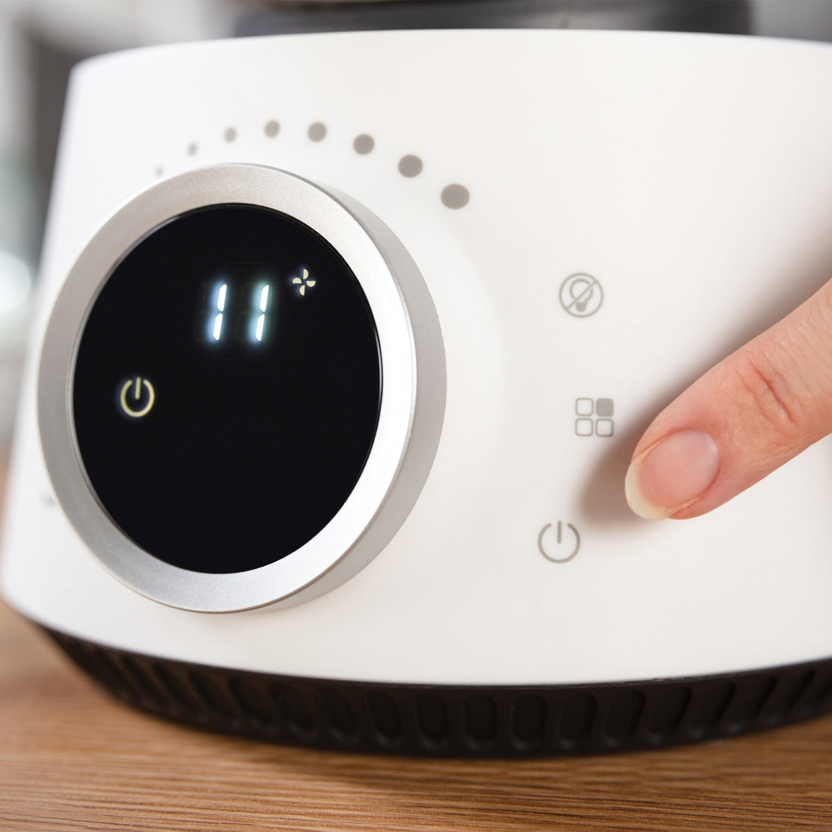 A finger presses the power button on the control panel of a white Igenix Digital Air Circulator Turbo Fan, which displays the number 11 on its circular screen.