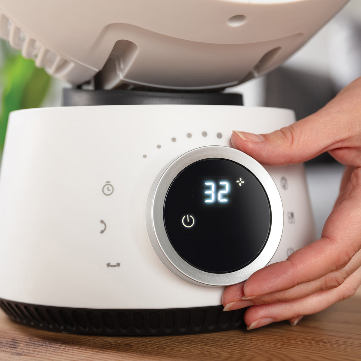 A hand adjusting the circular digital display on a white Igenix Digital Air Circulator Turbo Fan, 9 Inch, which features 32 wind speeds.