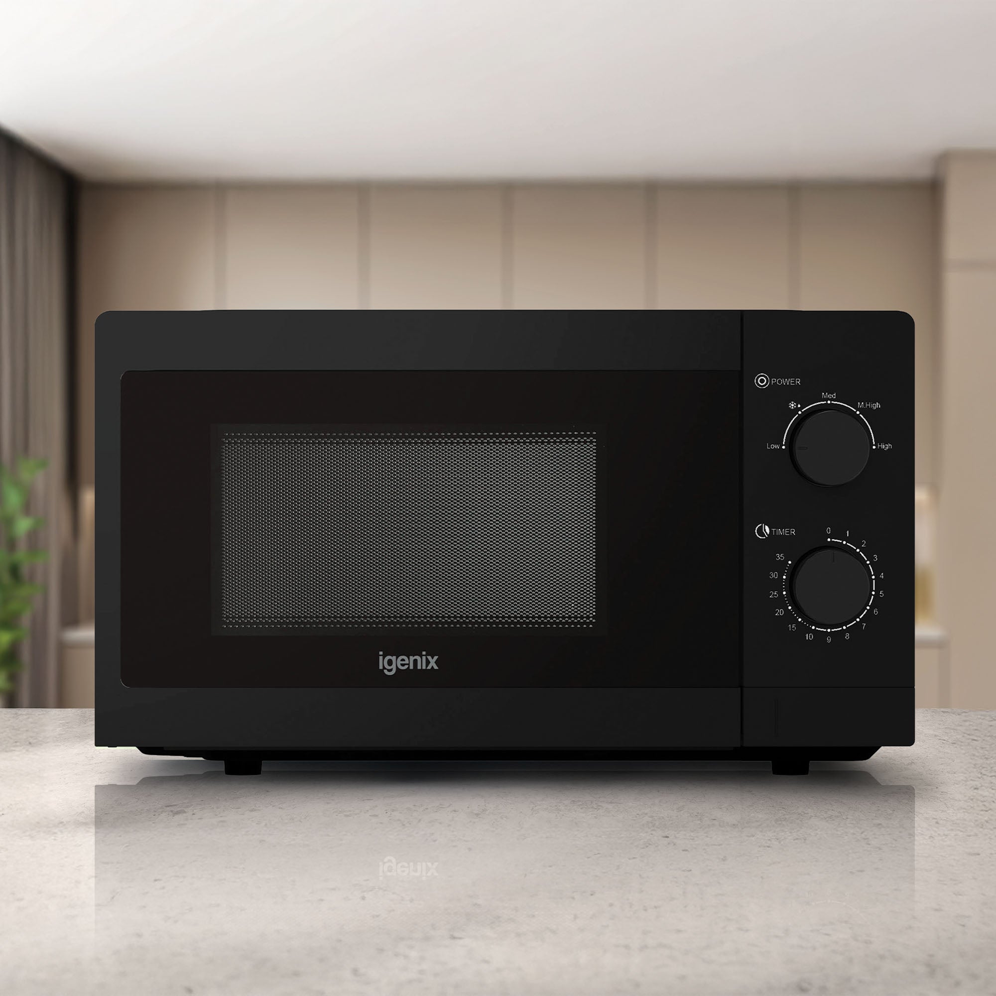 A sleek black Igenix IGMS08080B 20L manual microwave with 5 power settings and 800W sits on a light kitchen countertop, surrounded by beige cabinets and a softly blurred background.