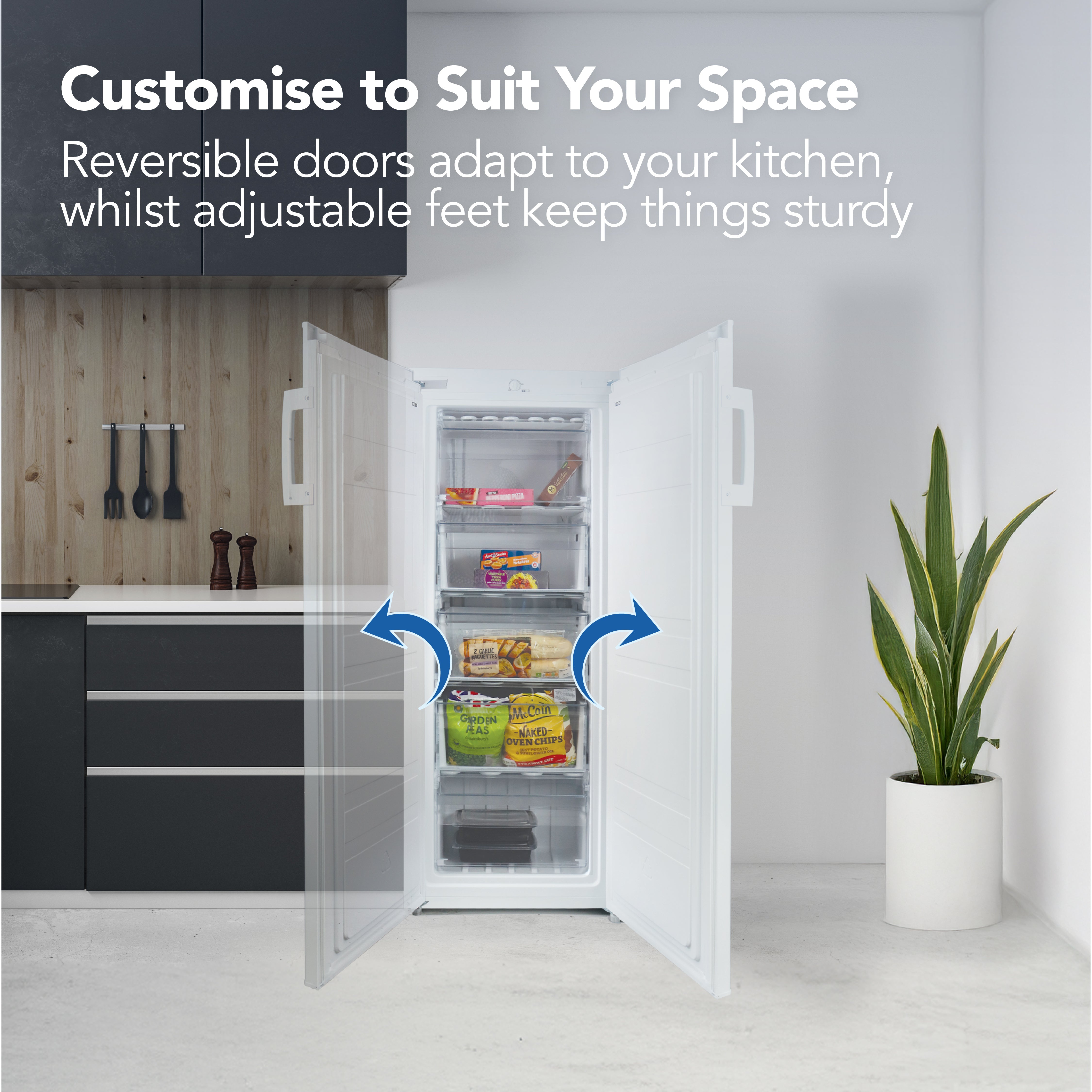 The Igenix Freestanding Tall Freezer (55cm wide, 160L) stands in a modern kitchen near black cabinets and wood paneling. Its reversible doors are open, showing food-filled shelves; blue arrows highlight its energy-efficient design.